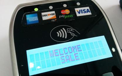 A payment terminal with an NFC payment logo compatible with Apple Pay and Google Wallet