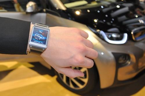 A BMW official shows off the all-electric i3 linked to a Samsung Galaxy Gear smartwatch at CES 2014. The watch can command the i3 to sound its horn and display info such as charge remaining in the battery. 